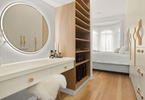 Renovated master suite and walk-in robe with custom cabinetry, new flooring, and featured wallpaper, round LED mirror