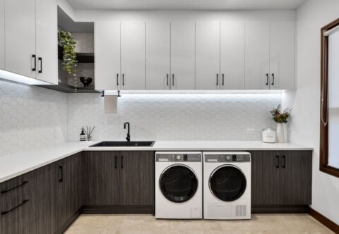 renovated modern laundry with hexagonal white tiles on splashback, black tapware and handles, new appliances and generous cupboards