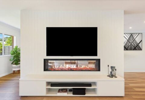 Renovated contemporary living room with double-sided fireplace, featured VJ panelling, custom cabinetry and vinyl flooring. Structural changes made by a licenced builder -Brilliant SA Renovations.