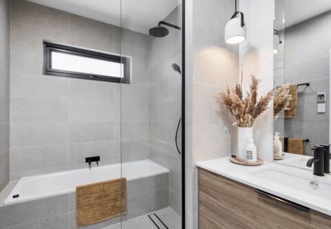 renovated bathroom, hexagonal feature tiles, built in mirror cabinet, engineered stone tops, wooden finish joinery with black accents and tapware, and a back to wall bathtub next to the walk-in shower.