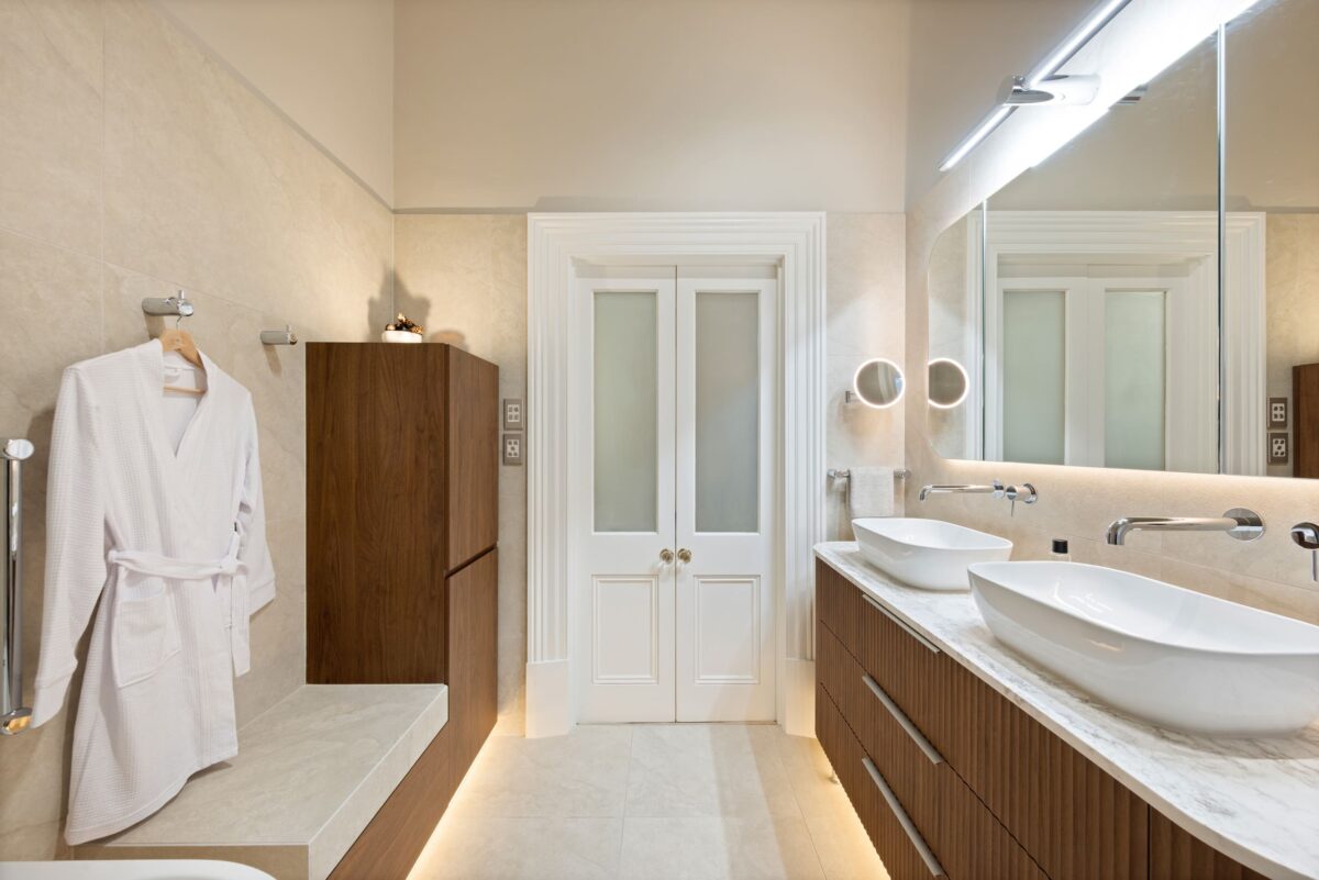 Renovated bathroom in Glenelg with a mid-century style, a double-basin vanity, shaving cabinets, layered lighting, and plenty of storage.