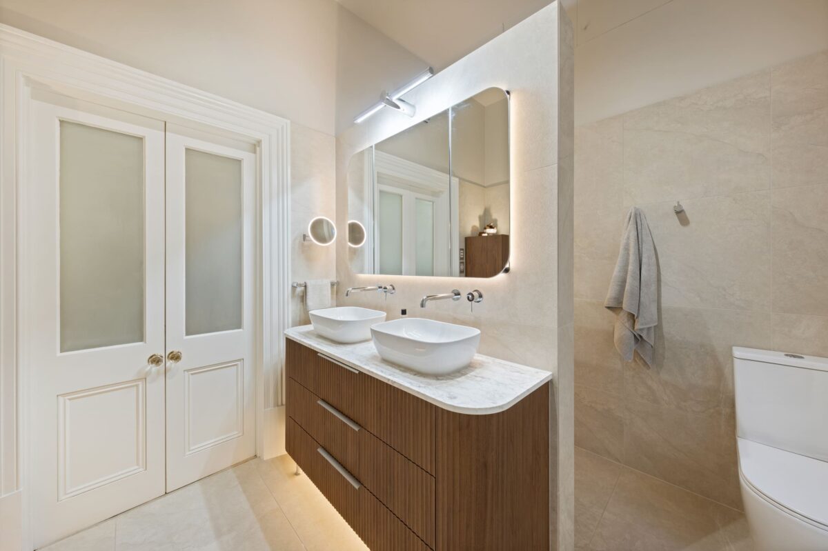 Renovated bathroom in Glenelg with a mid-century style, a double-basin vanity, shaving cabinets, layered lighting, and plenty of storage.