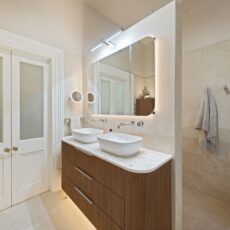 Renovated bathroom in Glenelg with a mid-century style, a double-basin vanity, shaving cabinets, layered lighting, and plenty of storage.
