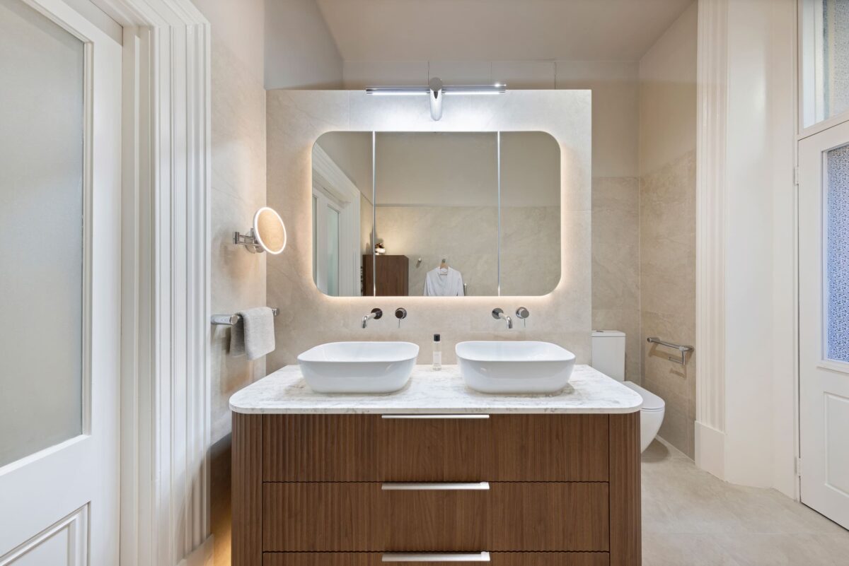Renovated bathroom in Glenelg, with a mid-century style, a double basin vanity, shaving cabinets, and layered lighting.