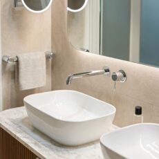 Renovated bathroom in Glenelg, with a mid-century style, a double basin vanity, shaving cabinets, and layered lighting.