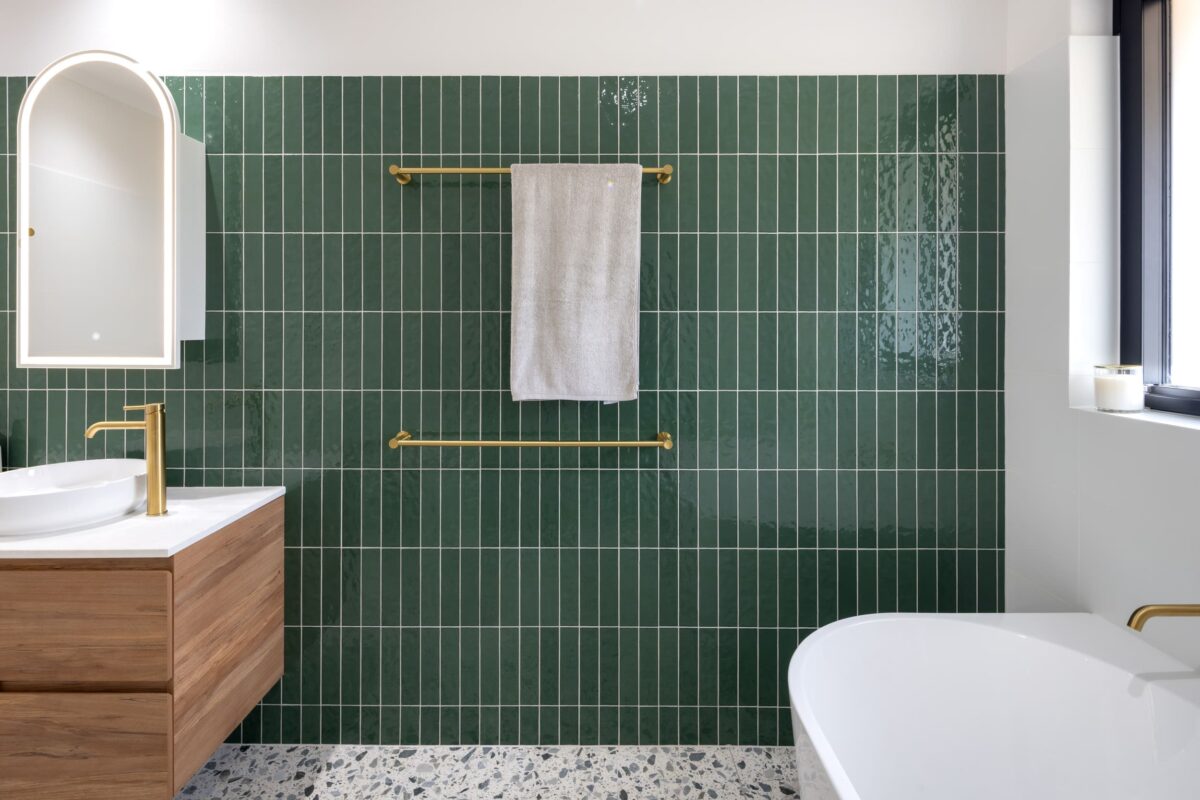 Renovated family bathroom with modern style, featuring green wall tiles and brushed brass accessories.