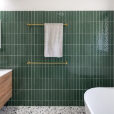Renovated family bathroom with modern style, featuring green wall tiles and brushed brass accessories.