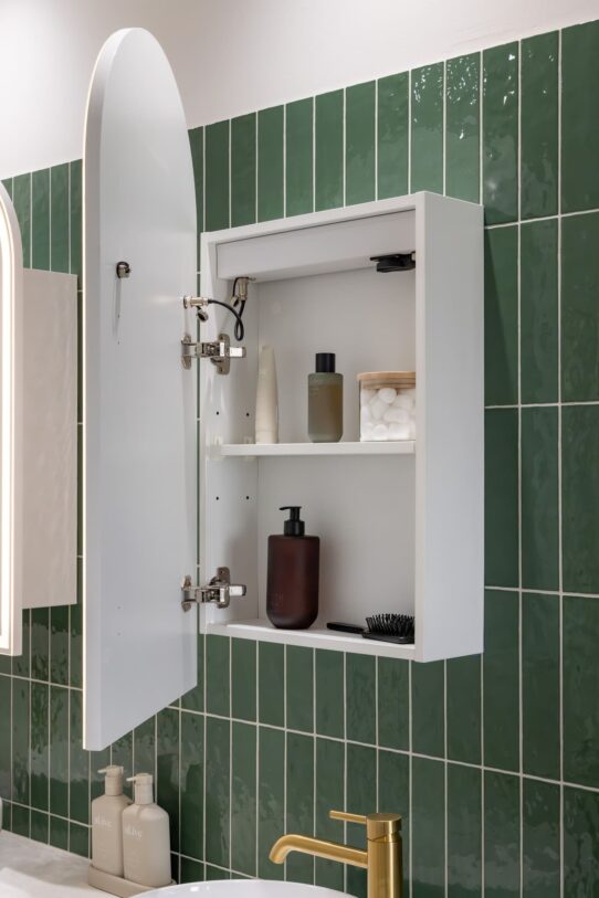 Renovated family bathroom with a modern style, featuring green wall tiles, twin mirror cabinets and brushed brass accessories.