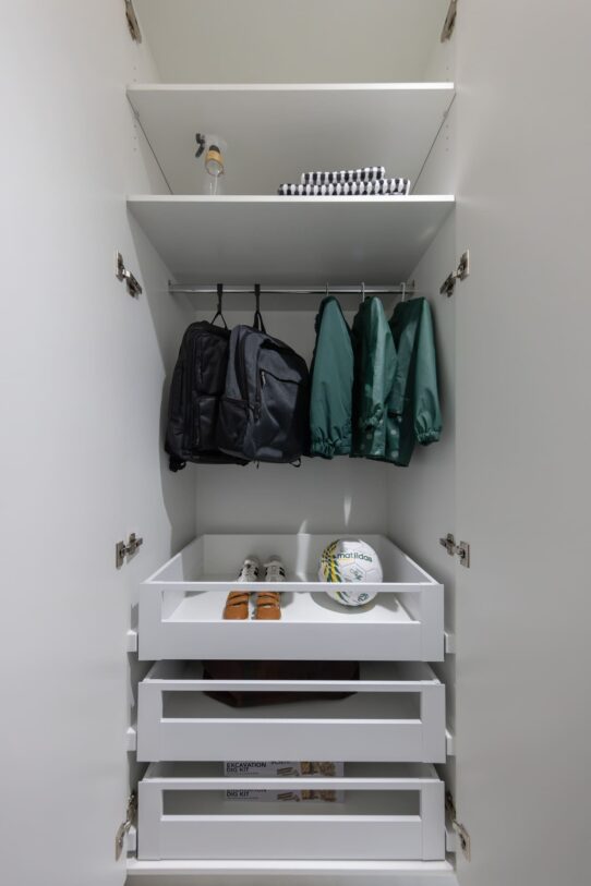 Renovated laundry room with a dedicated mudroom space, pullout drawers, a hanging rail for school bags and sports gear.
