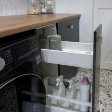 Renovated laundry room with dedicated storage for washing liquid and cleaning products adjacent to the washing and drying machines.