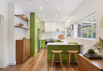 Renovated kitchen in Blackwood with retro-inspired style, vibrant green cabinetry, solid timber shelves and white benchtops.