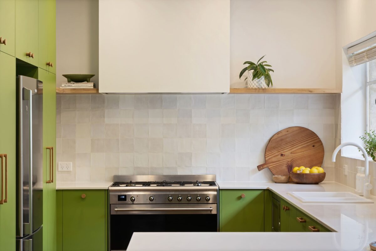 Renovated kitchen in Blackwood with retro-inspired style, vibrant green cabinetry, solid timber shelves and white benchtops.