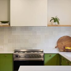 Renovated kitchen in Blackwood with retro-inspired style, vibrant green cabinetry, solid timber shelves and white benchtops.