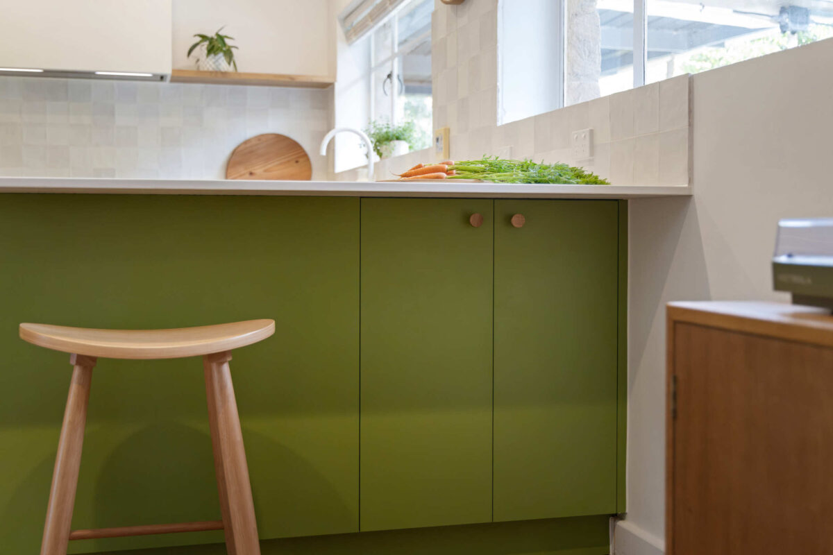 Renovated kitchen in Blackwood with retro-inspired style, vibrant green cabinetry, solid timber shelves and white benchtops.