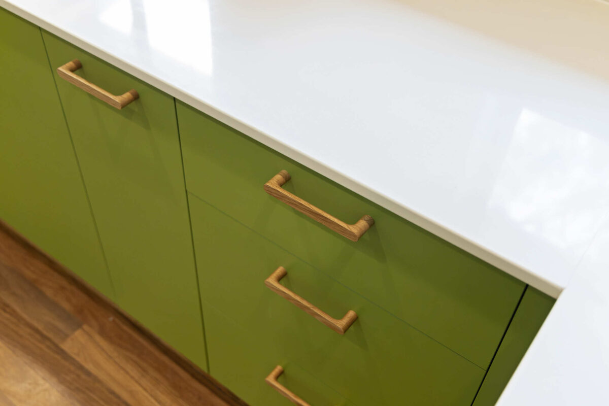 Renovated kitchen in Blackwood with retro-inspired style, vibrant green cabinetry, solid timber handles and white benchtops.