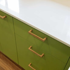 Renovated kitchen in Blackwood with retro-inspired style, vibrant green cabinetry, solid timber handles and white benchtops.